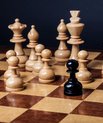 Chess board with a single black piece in the middle of all the white pieces.