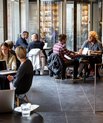 A modern looking cafe in which several people are sitting with their laptops.