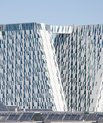 A powerful expressive work with two inclined and faceted towers connected by a sky bridge. The buildings are trapez shaped and made with white plates and glass.