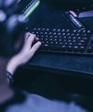 A young boy playing on his computer in a dark room.