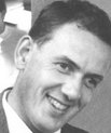 Black and white portrait photograph of youngish man smiling.