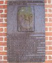 A metal plague with a face on it and some text