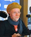 Portrait of Kalle Könkkölä sitting at a desk (seems like he is in the middle of being interviewed for a podcast)